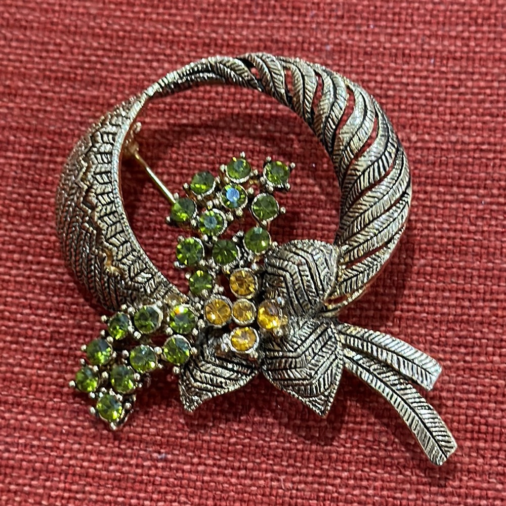 Gold tone brooch with green and good rhinestones.